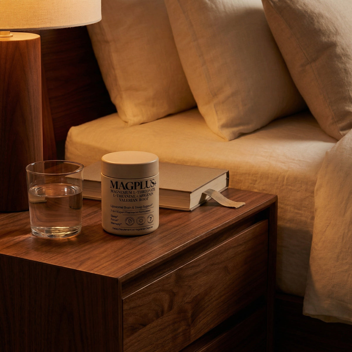 MAGPLUS supplement on dark walnut nightstand with warm amber lamp light — calm evening rest