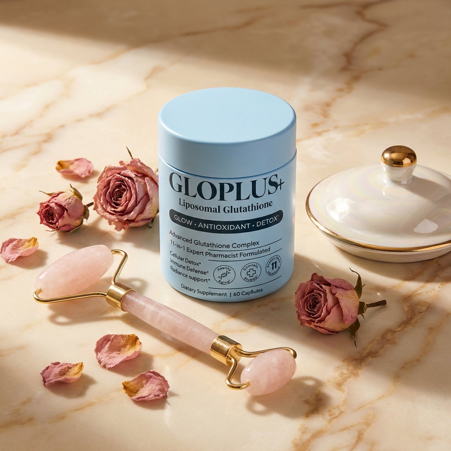GLOPLUS+ antioxidant supplement on cream marble with rose quartz facial roller and dried pink roses
