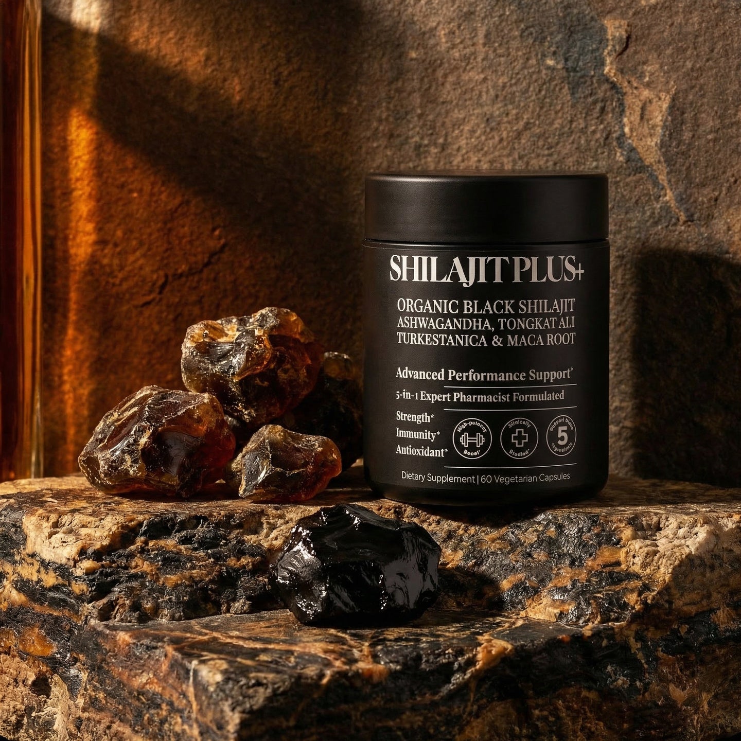 SHILAJITPLUS+ supplement on ancient dark stone surface with raw shilajit mineral resin and amber lighting